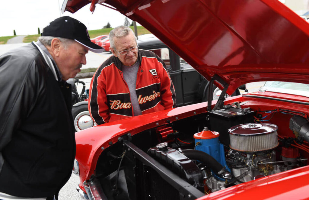 Two men examining the hood of a red car at a car show in at the Markets at Shrewsbury in Glen Rock, York County, Pennsylvania.