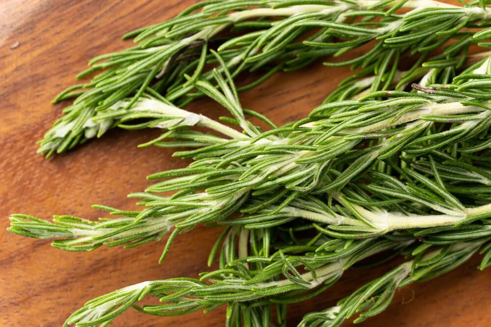 close up of sprigs of rosemary on a wooden cutting board