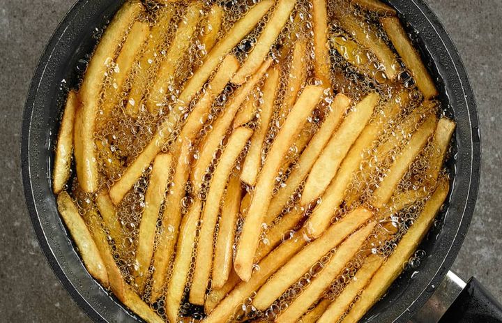 Homemade french fries cooking in oil in a dutch oven pot