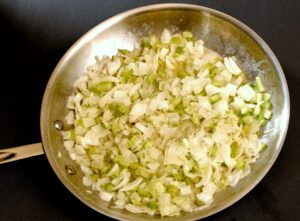 A person sautes onion and celery for PA Dutch potato filling.