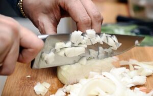 A person chopping a white onion for PA Dutch potato filling