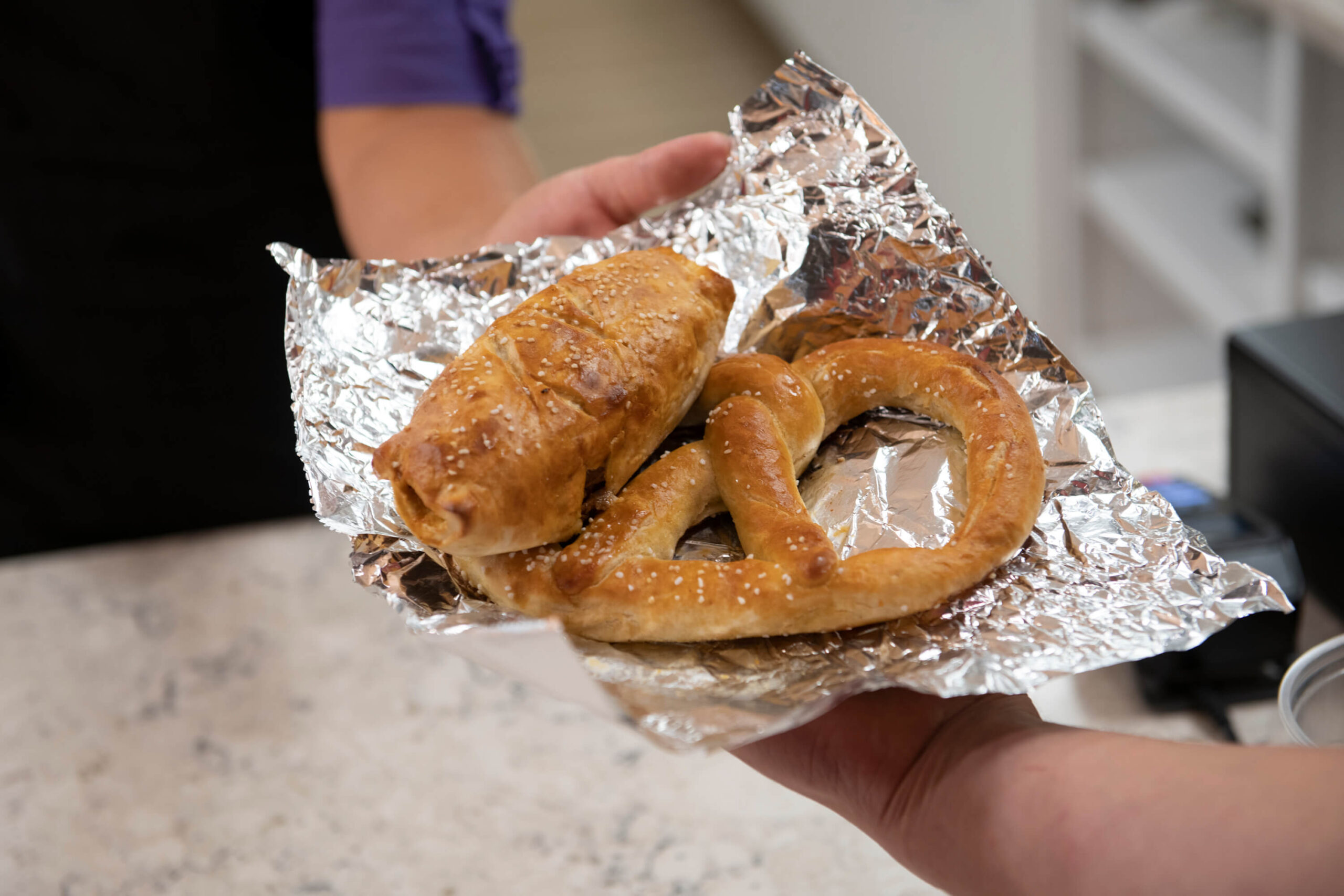 close up of a person handing of pa dutch pretzels to another person