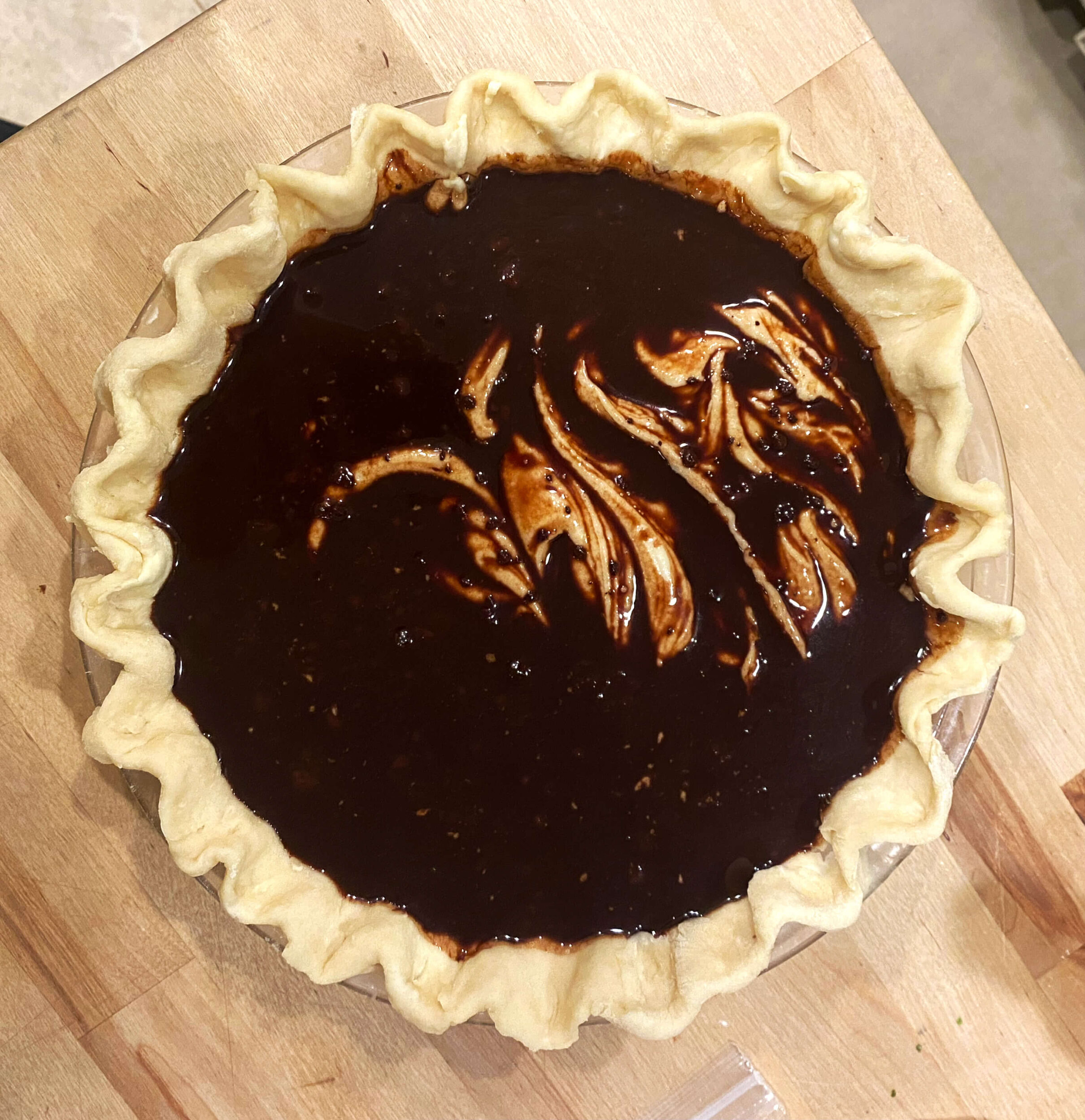 an unbaked funny cake with the chocolate sauce sitting in the pie crust